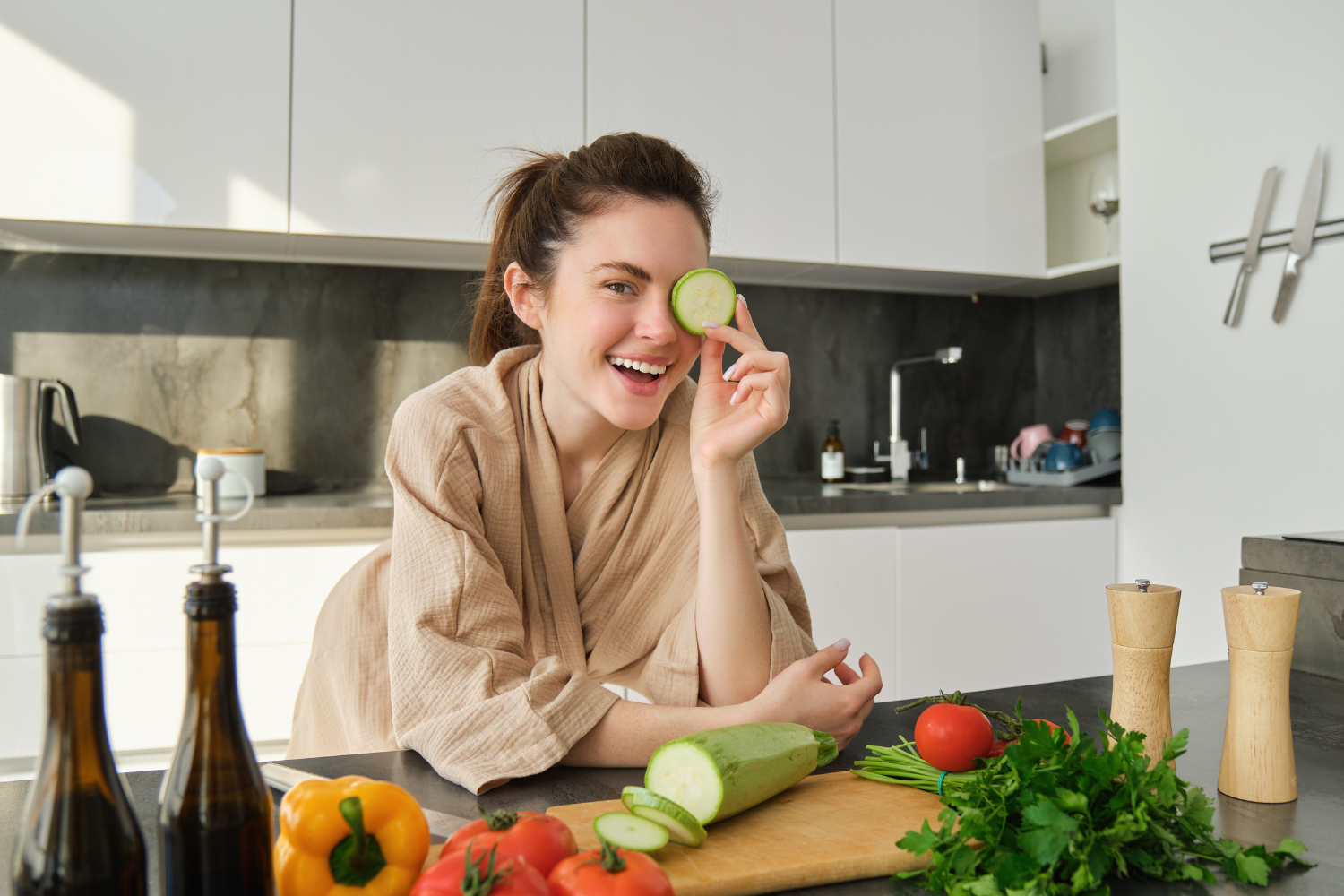 Happy woman holding cucumber slice in kitchen