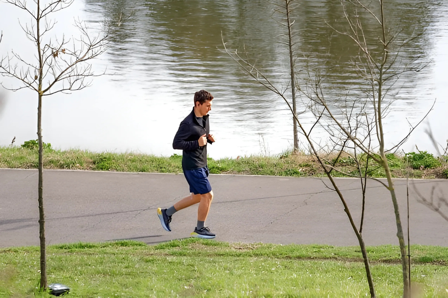 Man jogging by a lake on sunny day