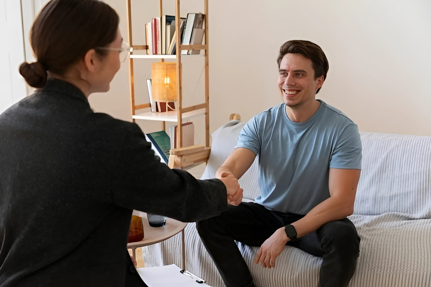 Smiling man shaking hands with therapist indoors