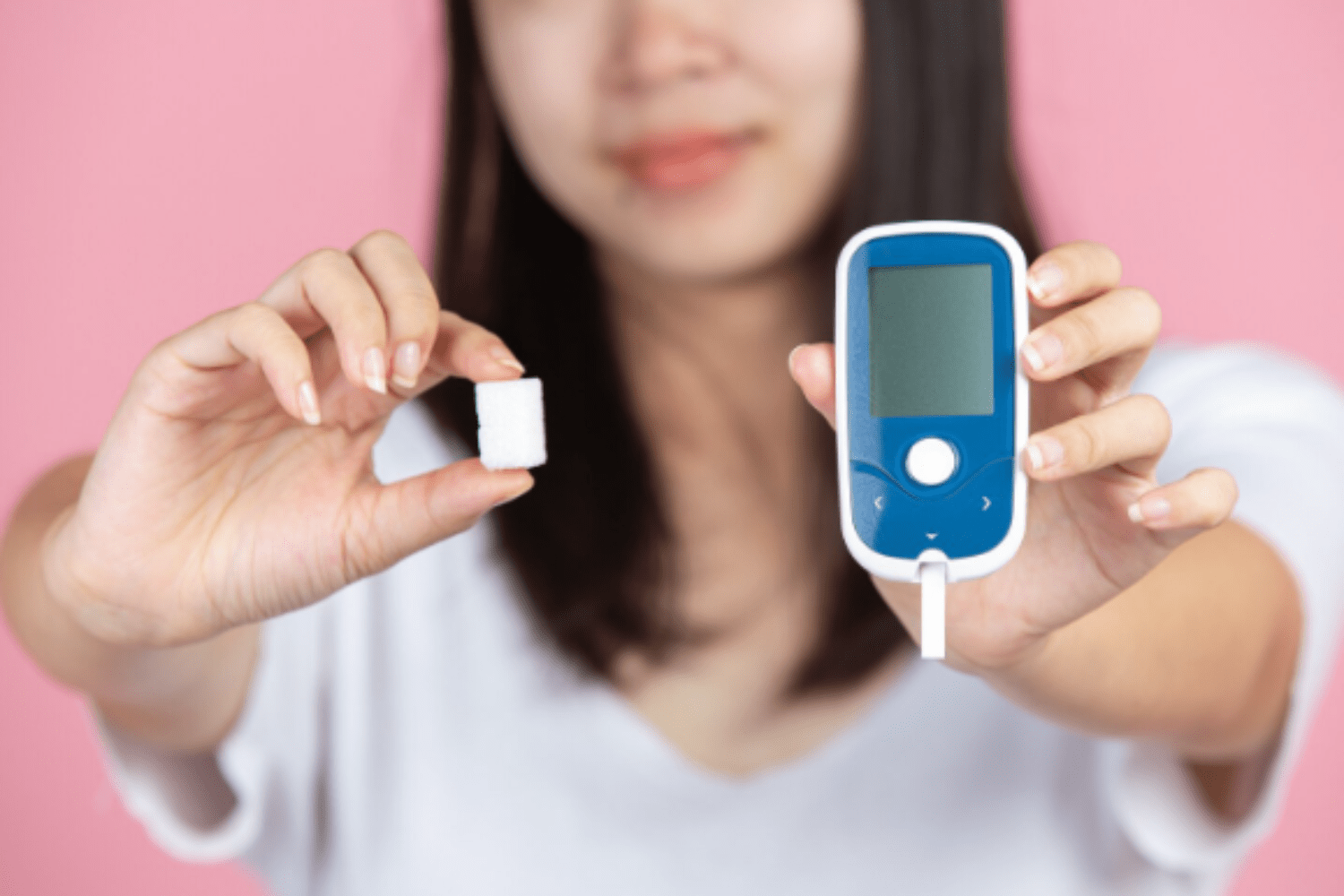 Woman holding sugar cube and glucose monitor
