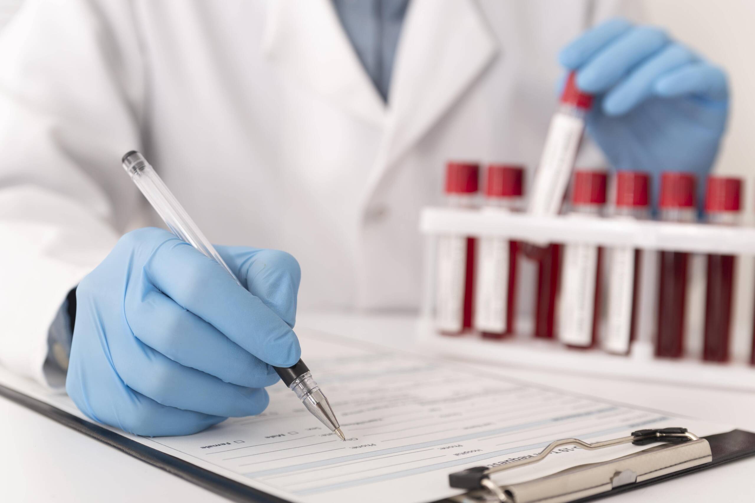 Doctor writing lab form with blood samples nearby
