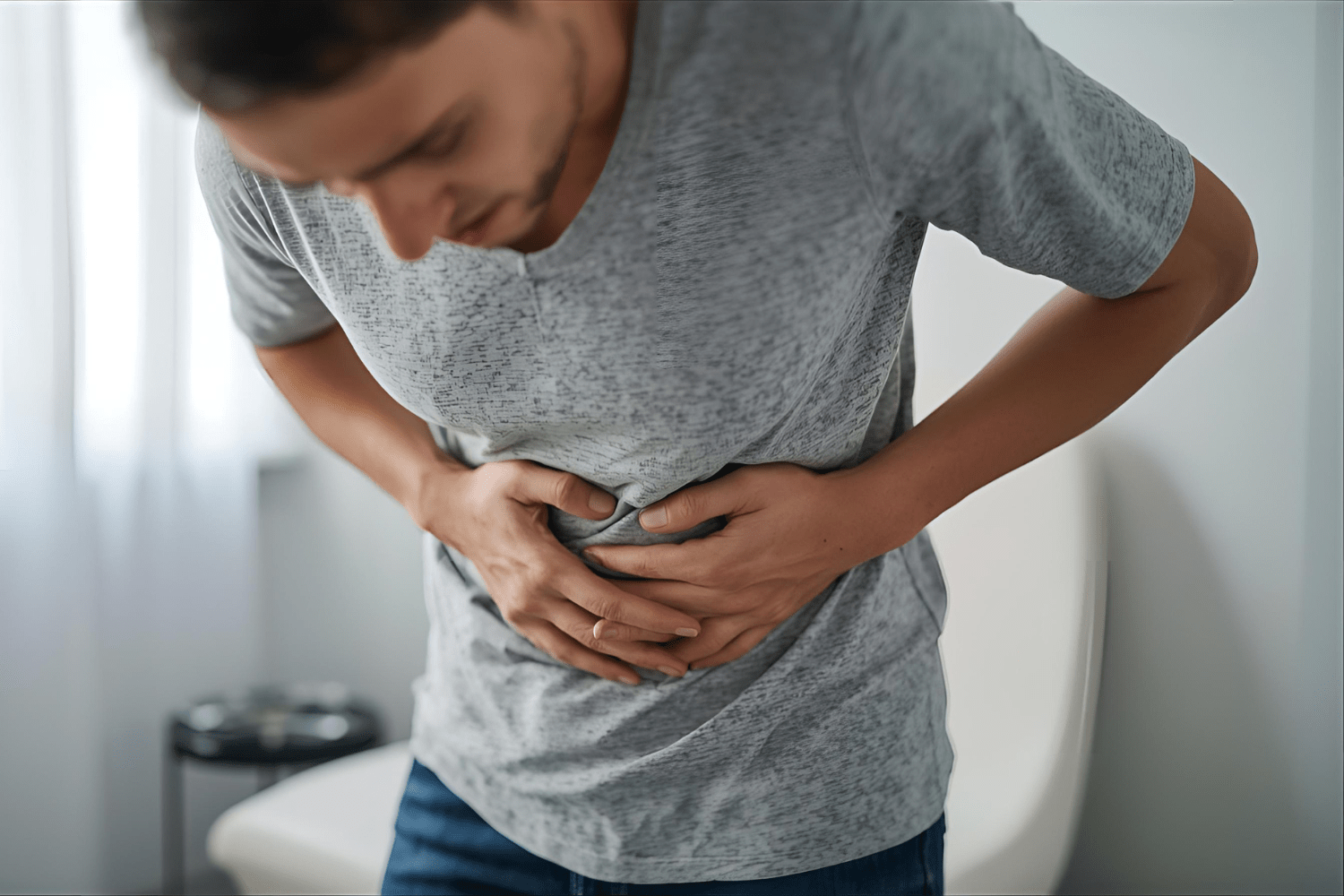 Man clutching stomach in pain, showing abdominal discomfort.

